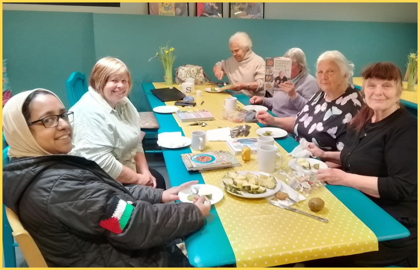 6 members of New Wortley Community Centre's Lunch Club sit around a table sharing a meal